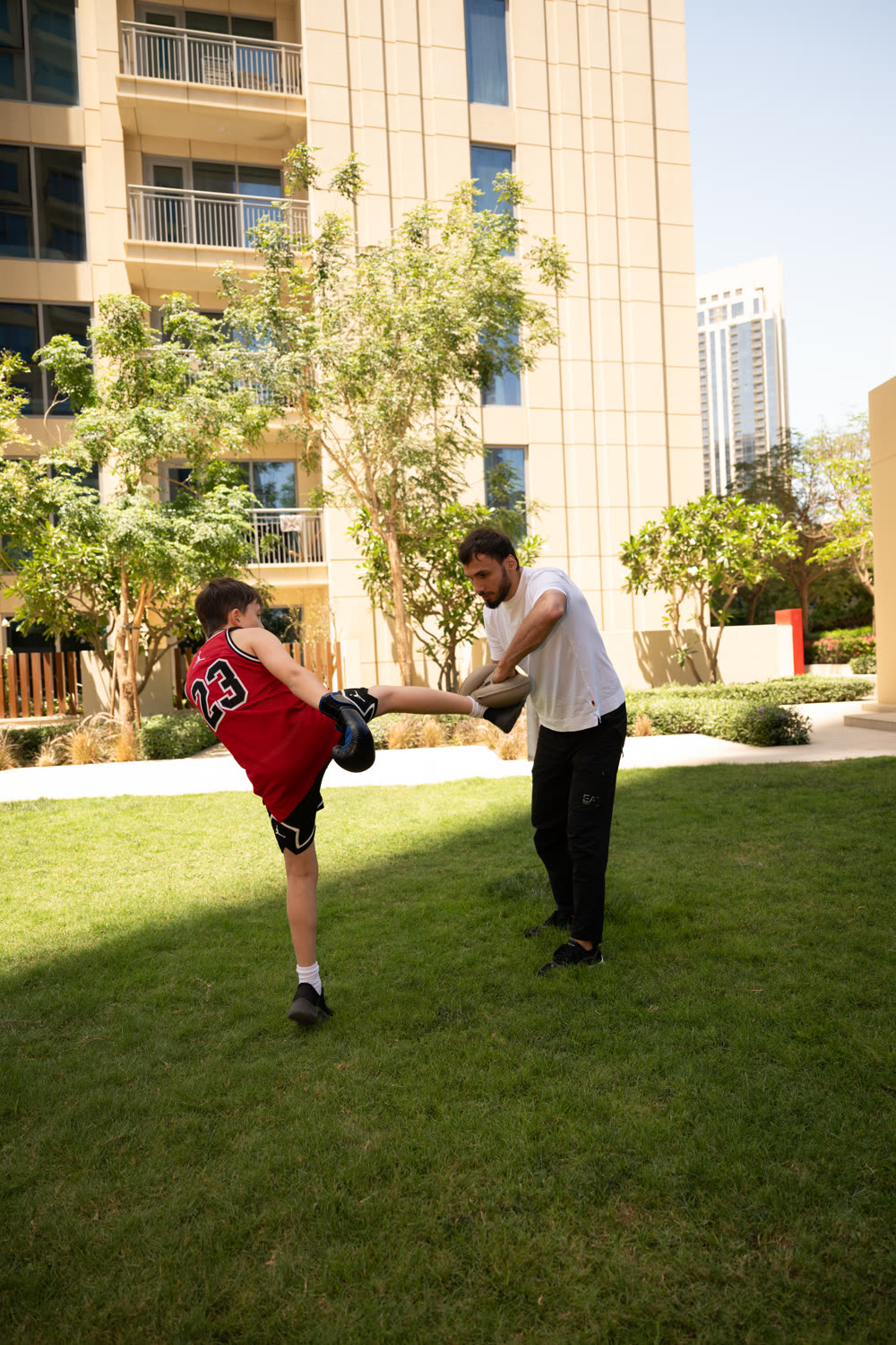 Kid practising a kick with Illias holding the pad